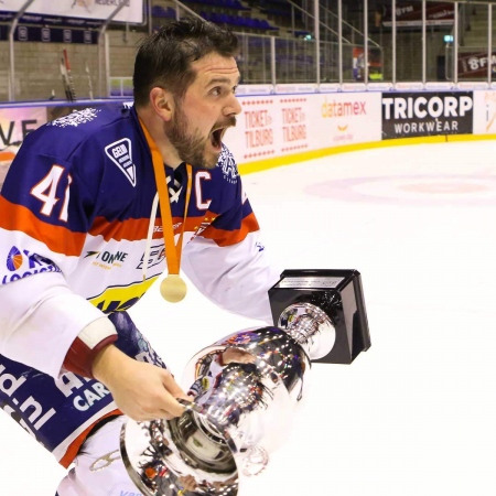 Levi Houkes schaatst met de beker richting zijn medespelers