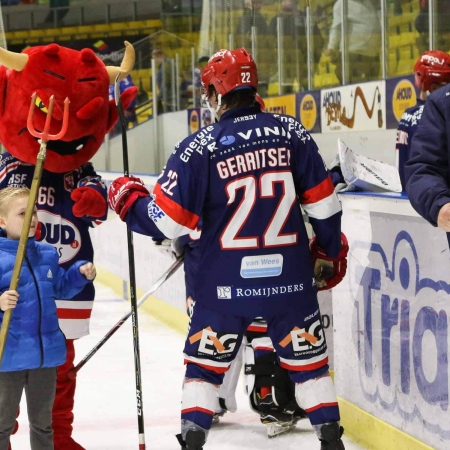 De mascotte tikt de spelers van het ijs.