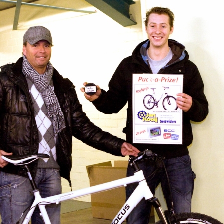 Jean Paul Broere reikt fiets uit aan Jordy Mater als prijs van het puck gooien